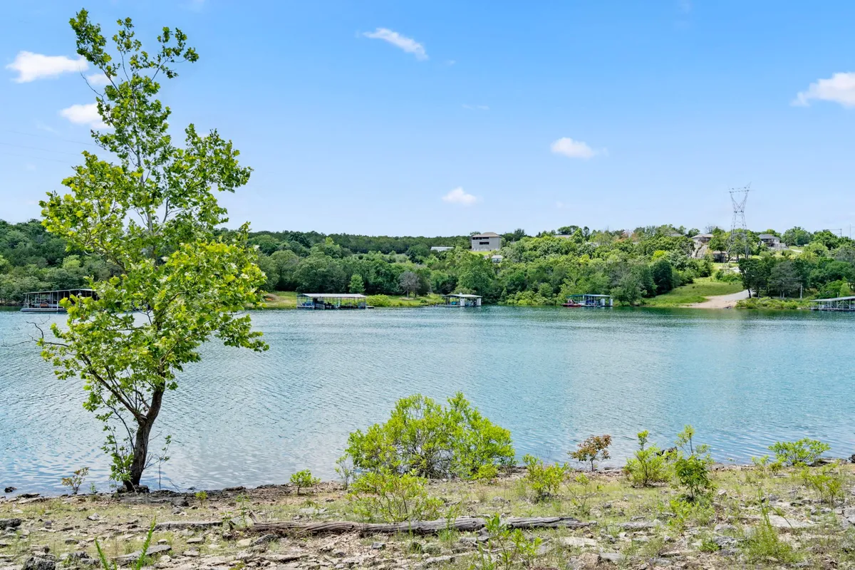 A tranquil lakeside scene showing the calm waters of Table Rock Lake, framed by leafy trees and a distant shoreline under a clear sky. The mood is peaceful, ideal for fishing, boating, or enjoying a lakeside picnic.