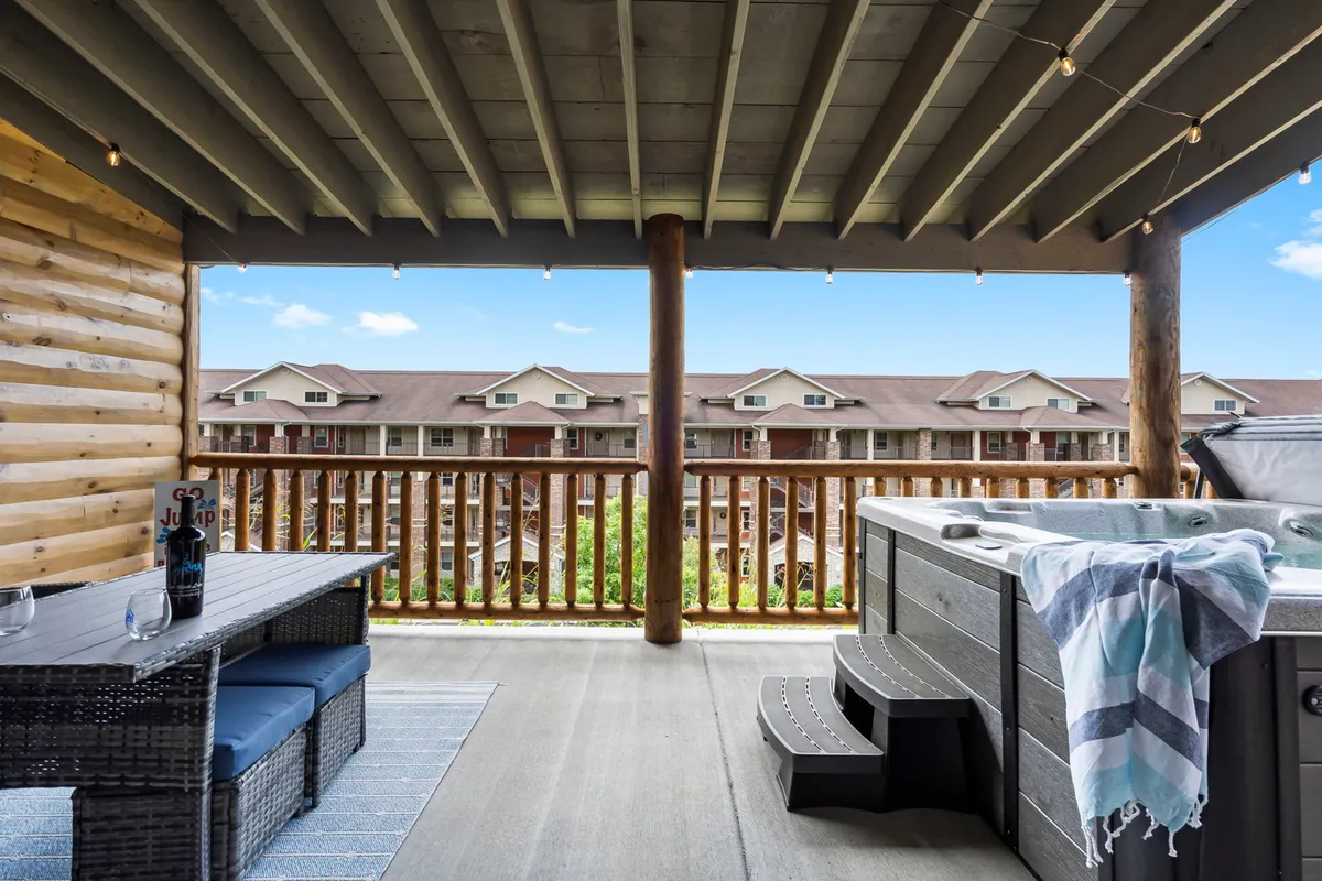 A cozy outdoor space with a bubbling hot tub, comfortable seating area, and a beautiful view from the balcony. The setup is perfect for unwinding after a day of outdoor activities, surrounded by natural beauty.